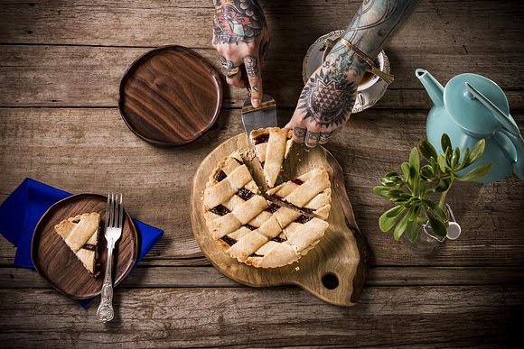 Pie on handmade wood tray with tattooed hands